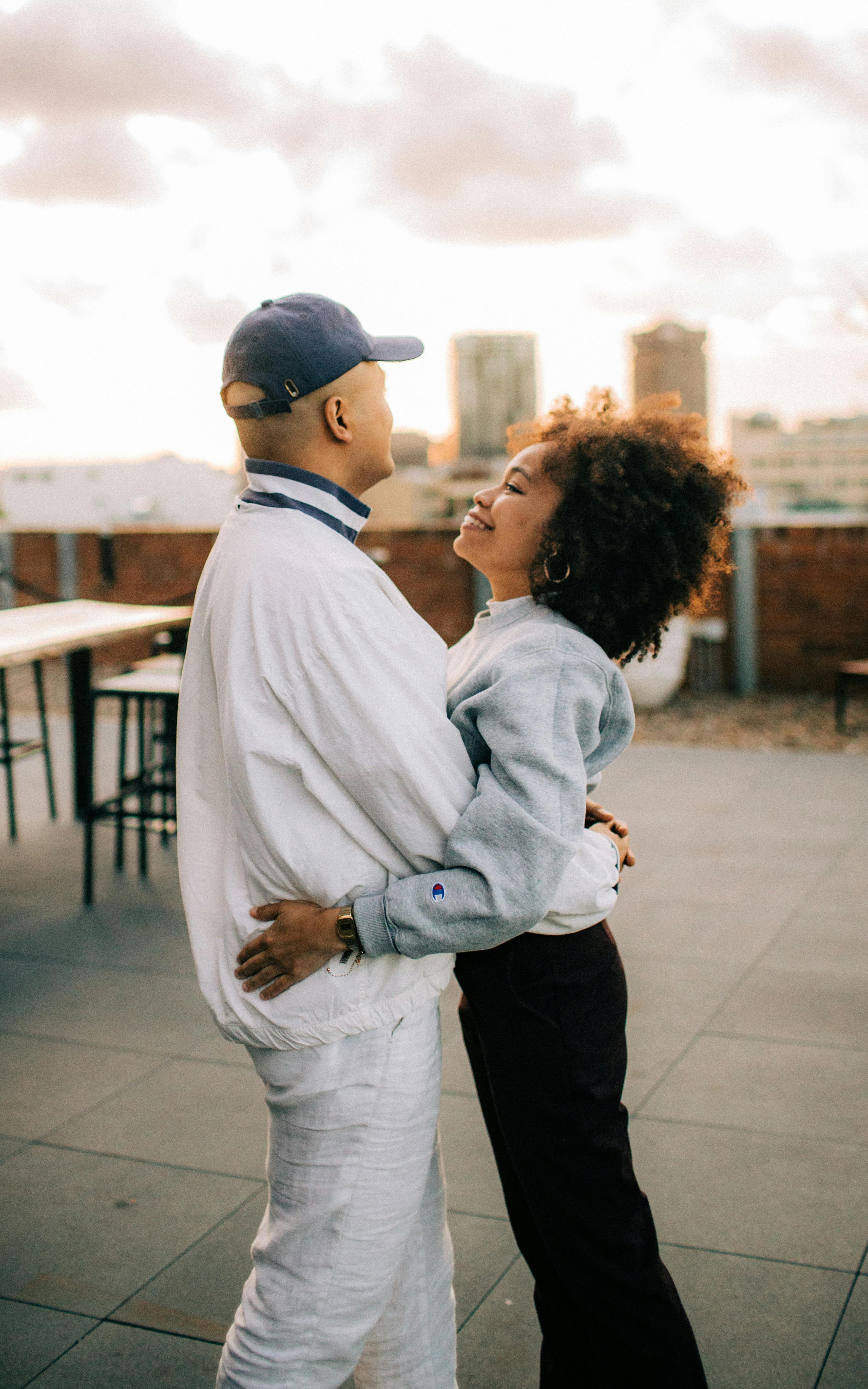 Romantic couple hugging on a rooftop, enjoying a sunny day together.