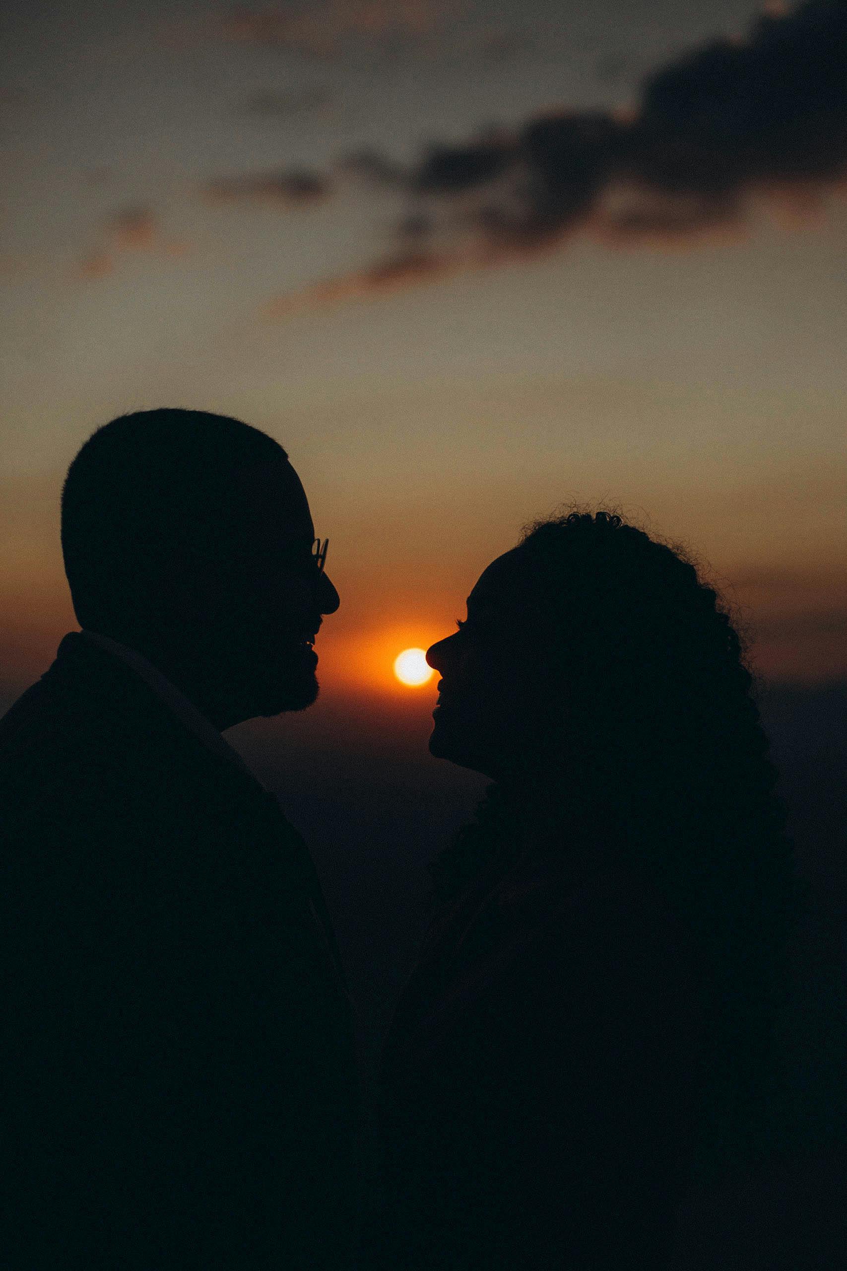 Silhouetted couple in loving gaze at sunset, capturing romance and serenity.