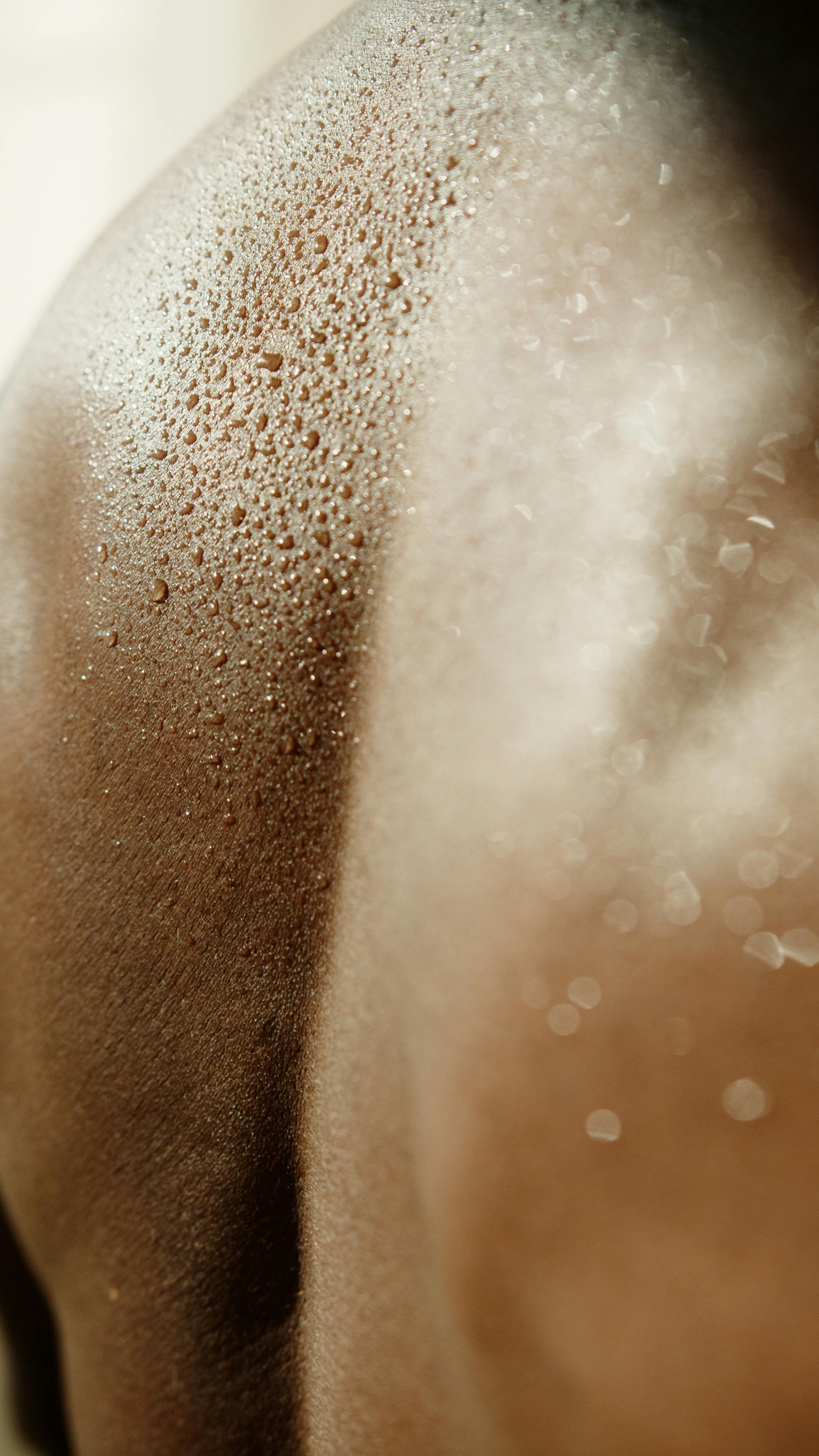 Detailed close-up showing sweat droplets on human skin, highlighting texture and hydration.