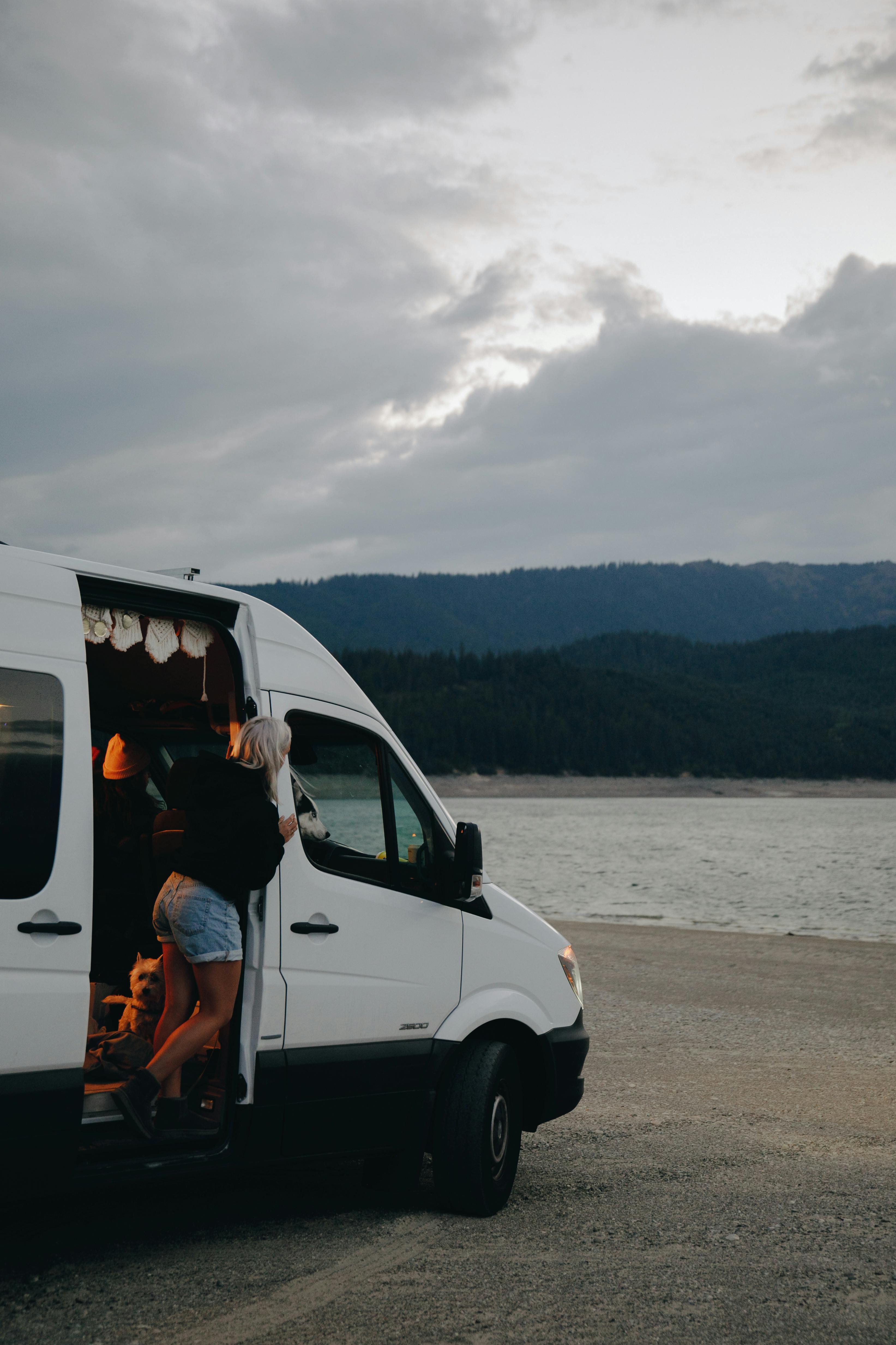 Explore a serene lakeside camping scene with a campervan under a cloudy sky.