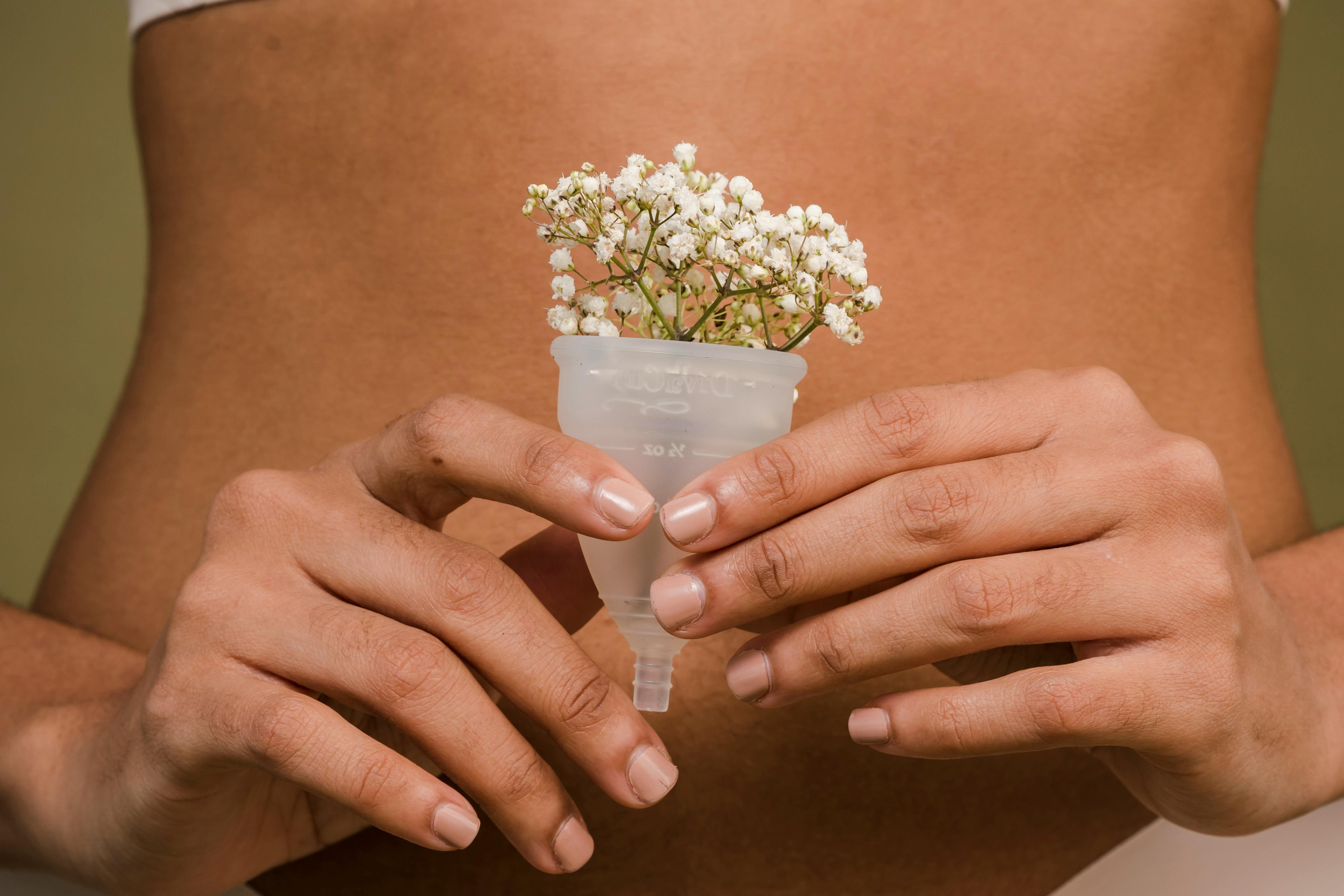 A creative depiction of femininity with a menstrual cup and flowers, emphasizing health and intimacy