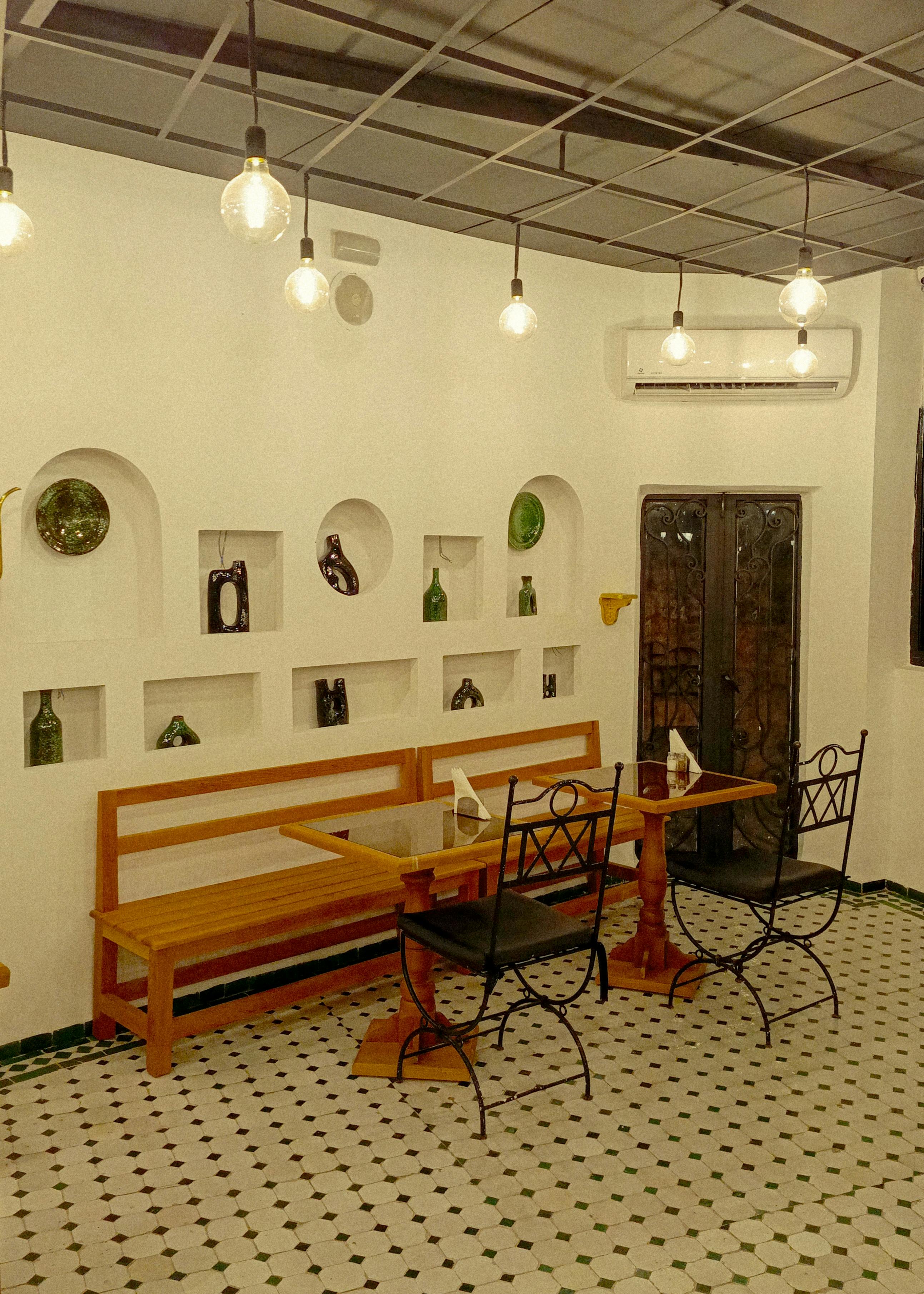 Stylish indoor cafe setting with art-filled walls, vintage chairs, and warm lighting.