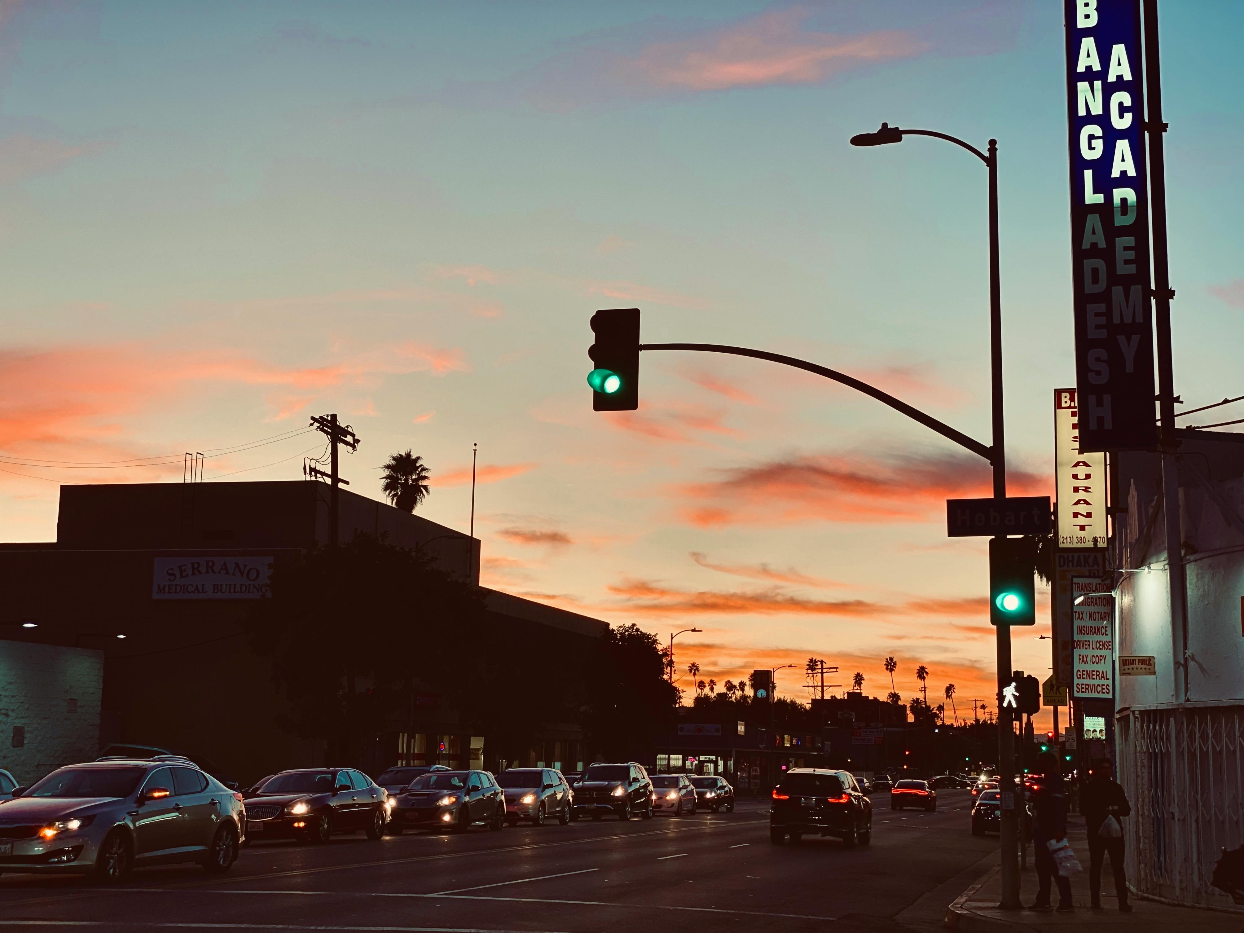 City street view during sunset with traffic lights and vehicles.