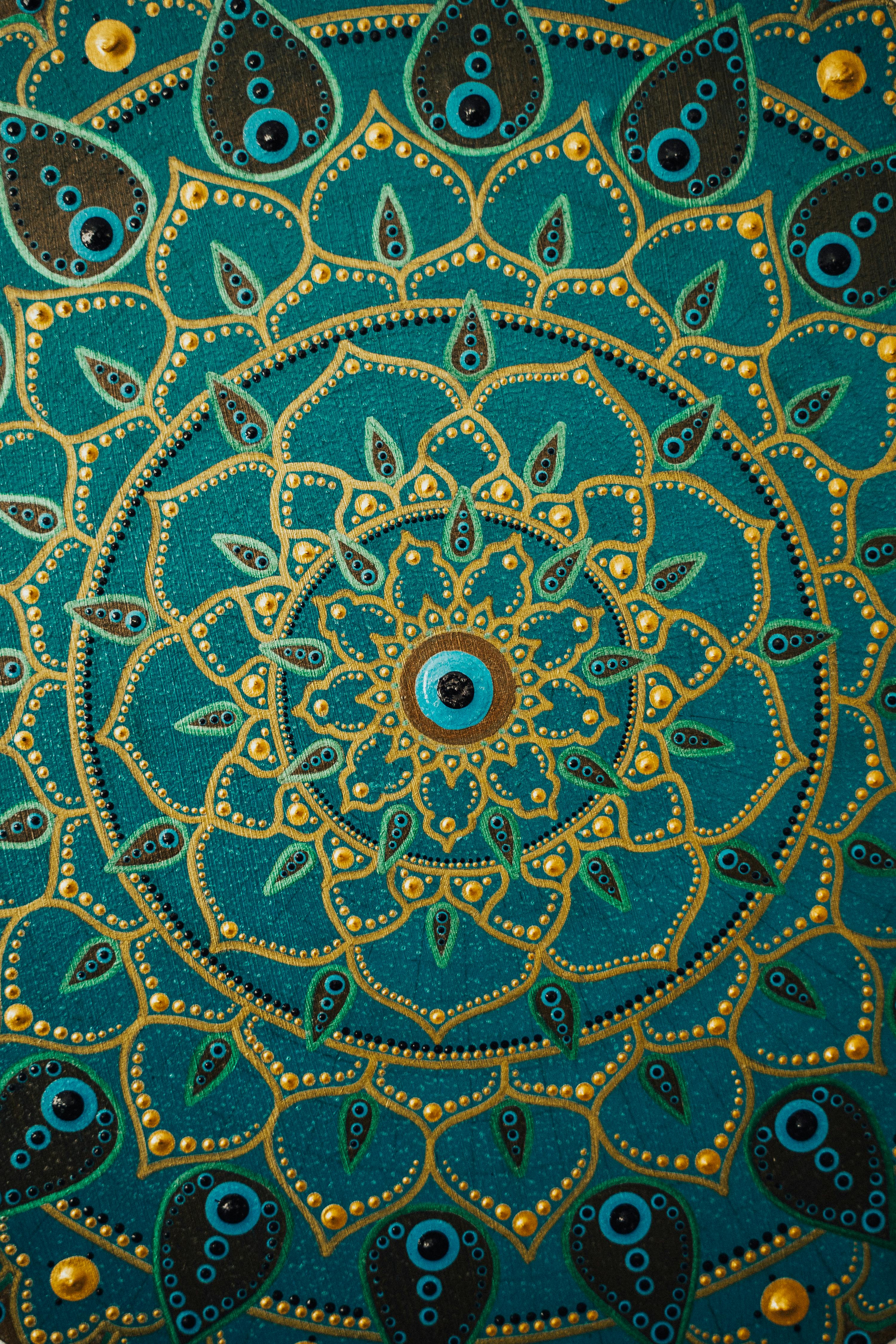 Detailed dot painting mandala artwork on teal background showcasing vibrant, intricate patterns.