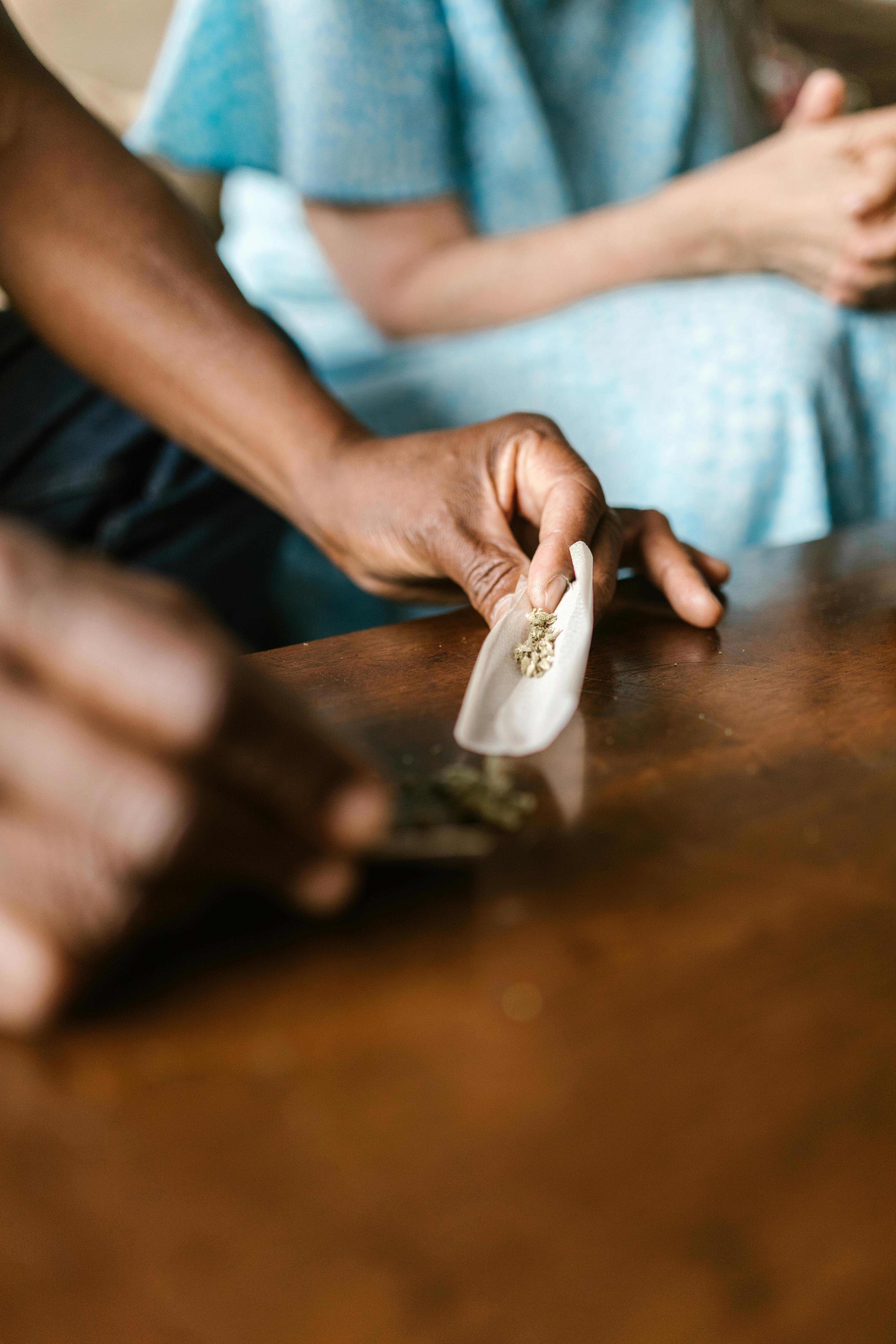 Detailed view of hands rolling a marijuana joint, emphasizing the process and texture.