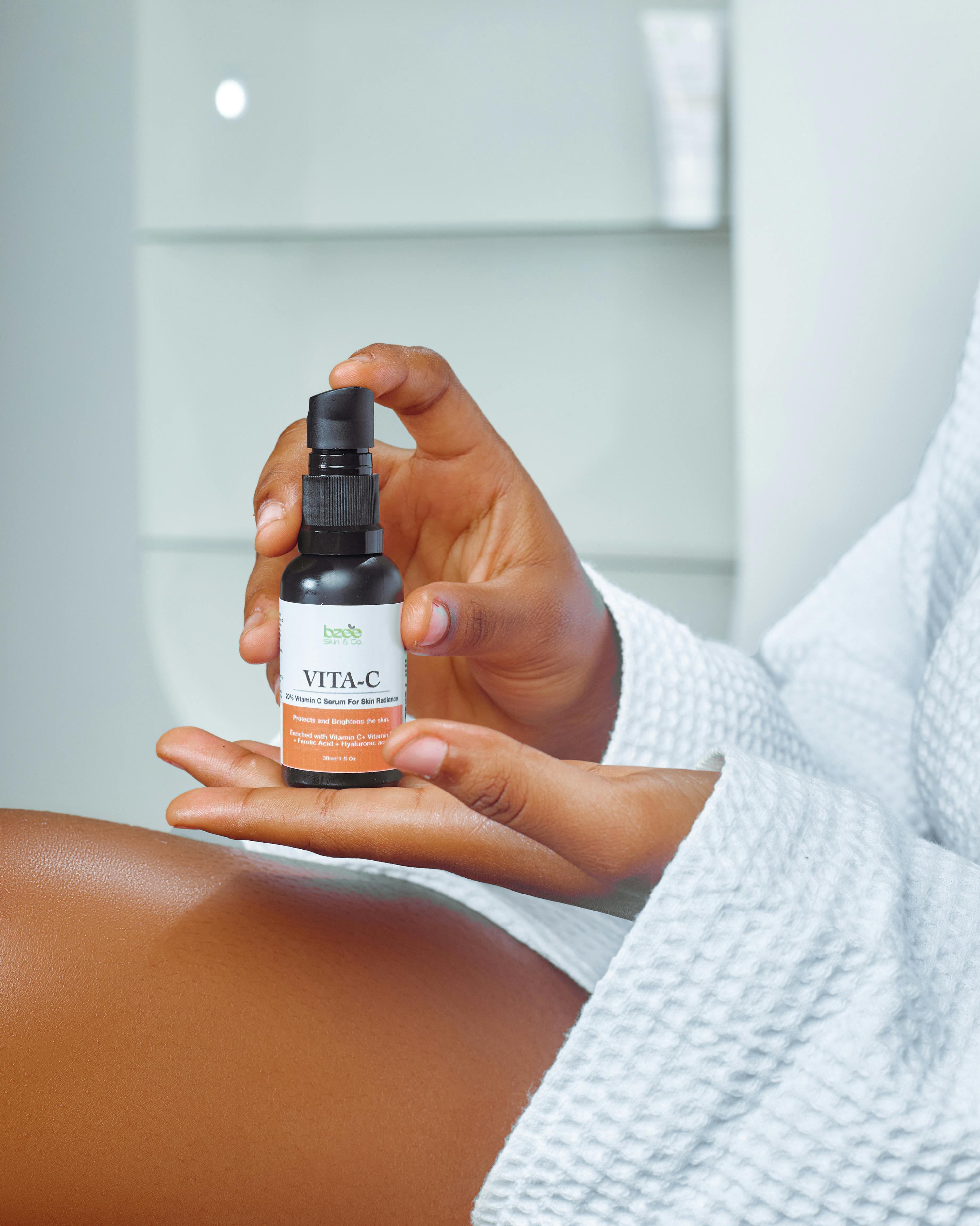 Close-up of a woman holding a Vitamin C skincare product in a modern setting.