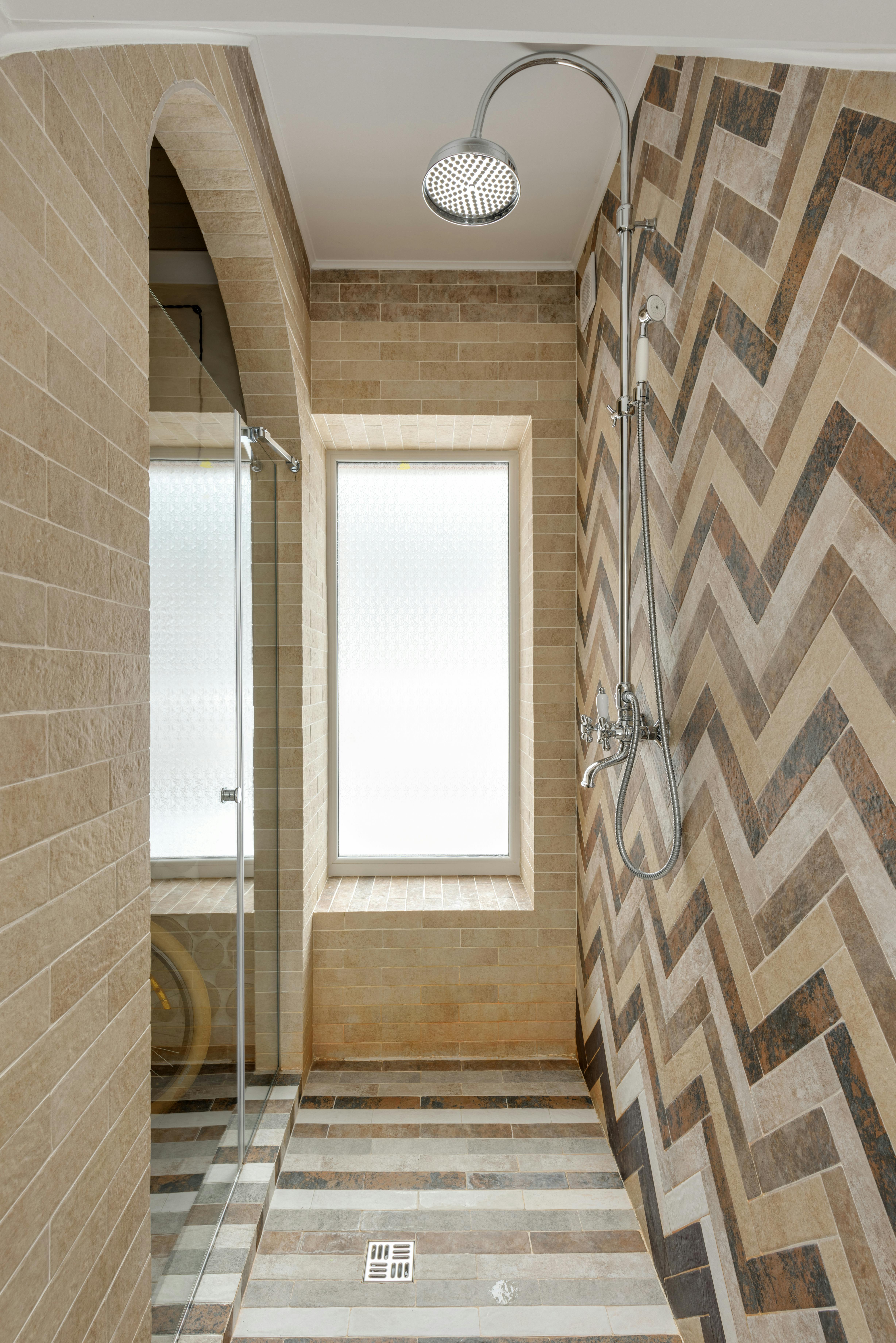 Luxurious shower interior with chevron tile pattern and modern glass door.