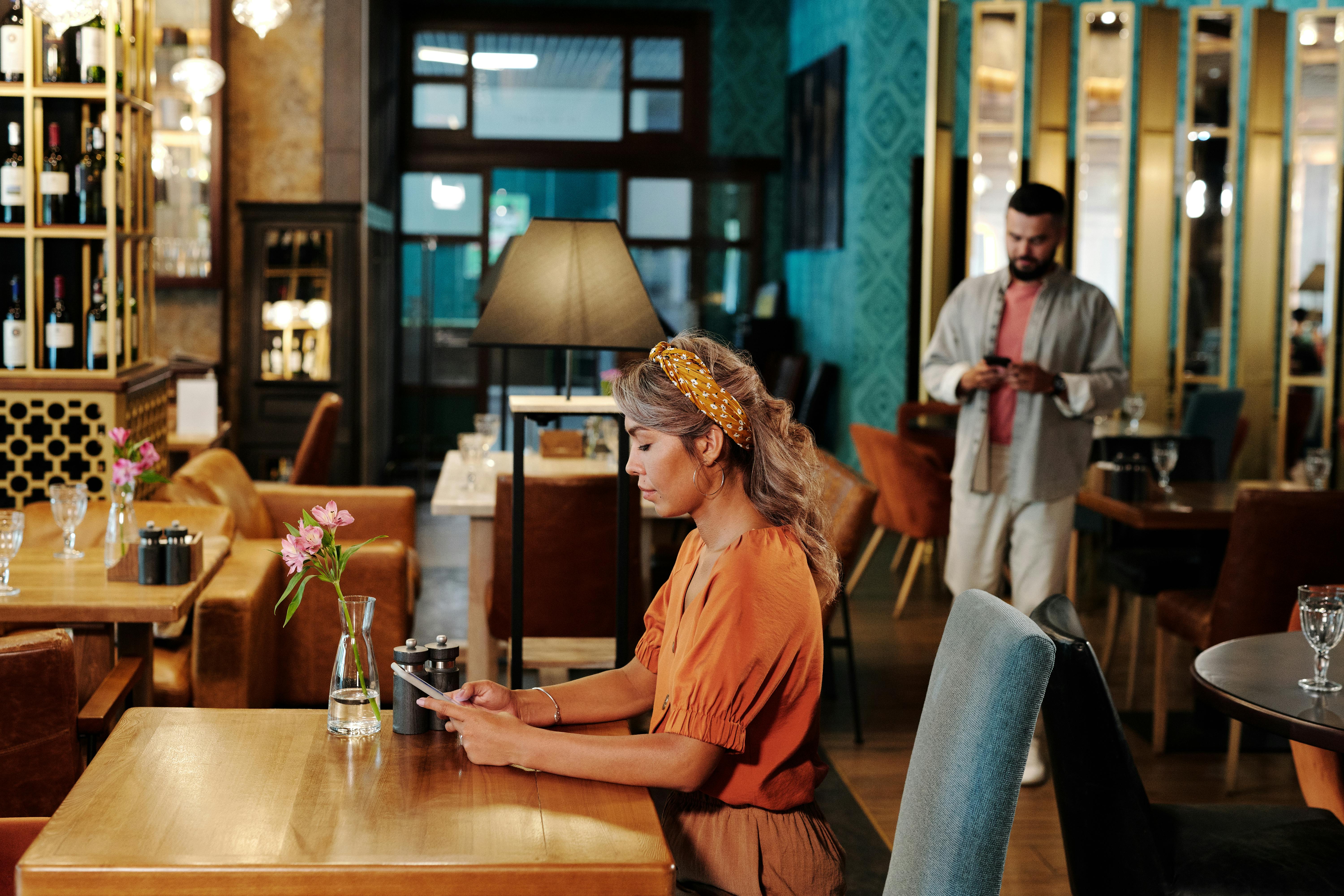 Two individuals engrossed in smartphones at a stylish cafe.