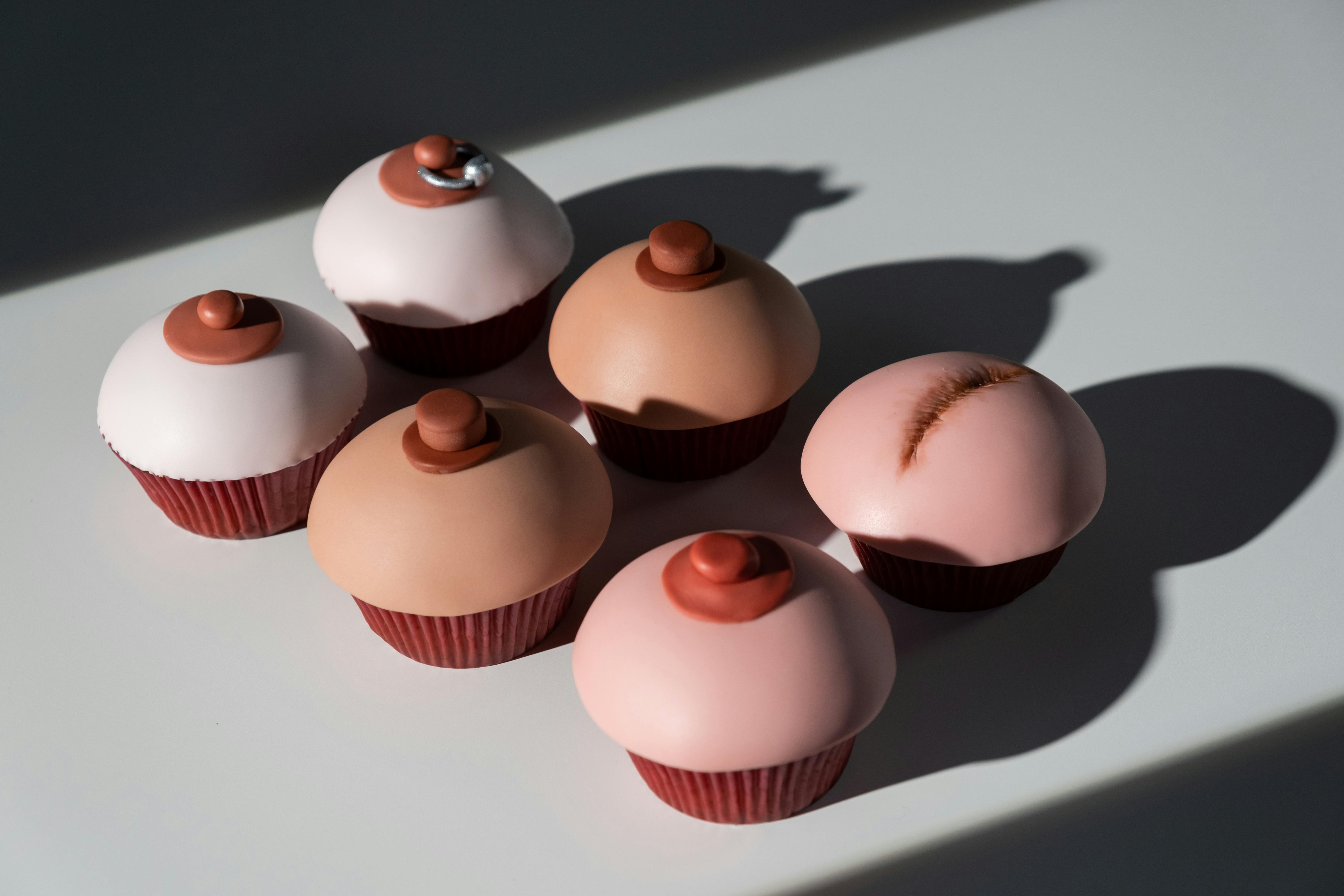 Creative cupcakes designed for breast cancer awareness in a flat lay composition highlighting diversity and support.