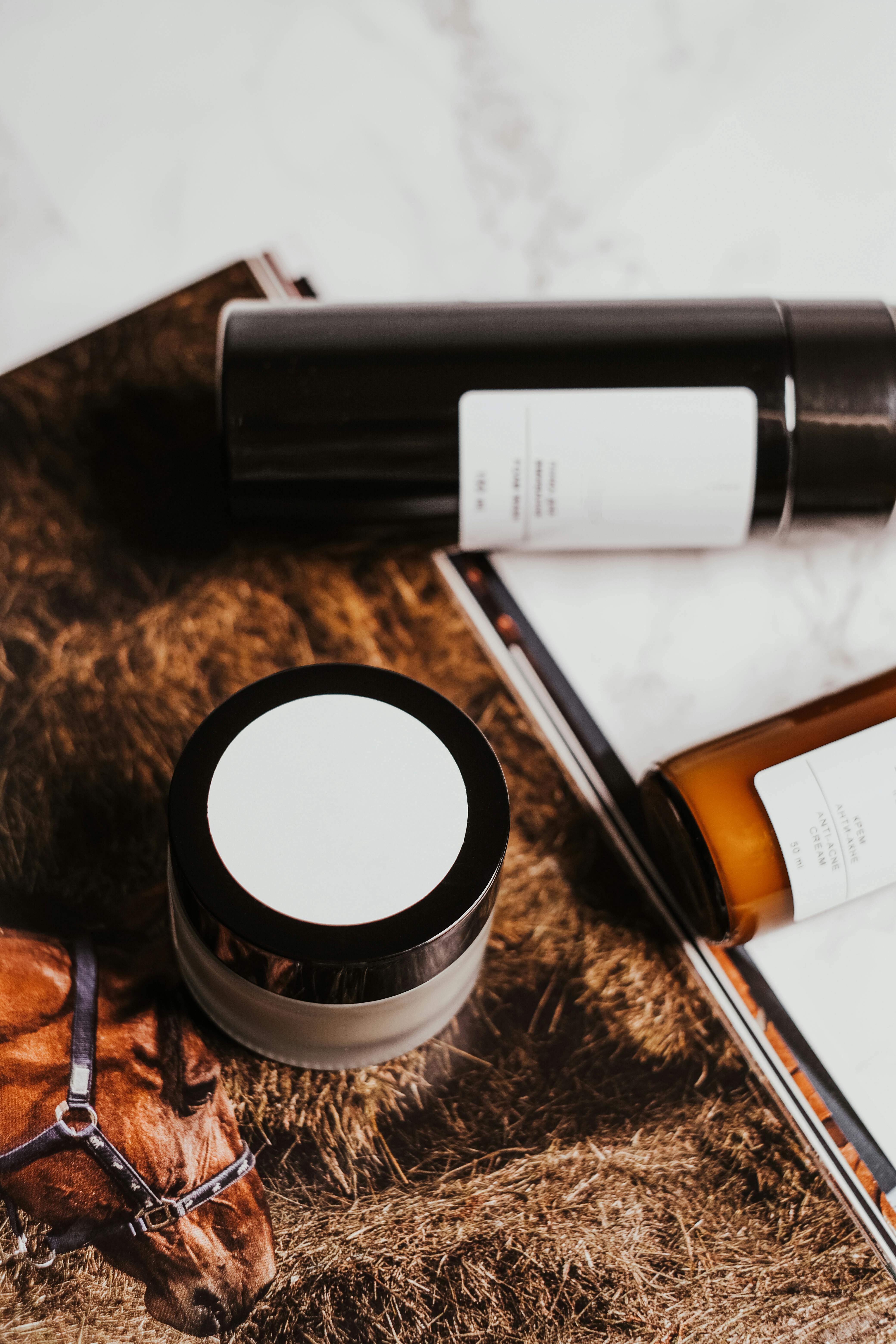 Minimalist display of cosmetic products on a marble background with earthy aesthetics.