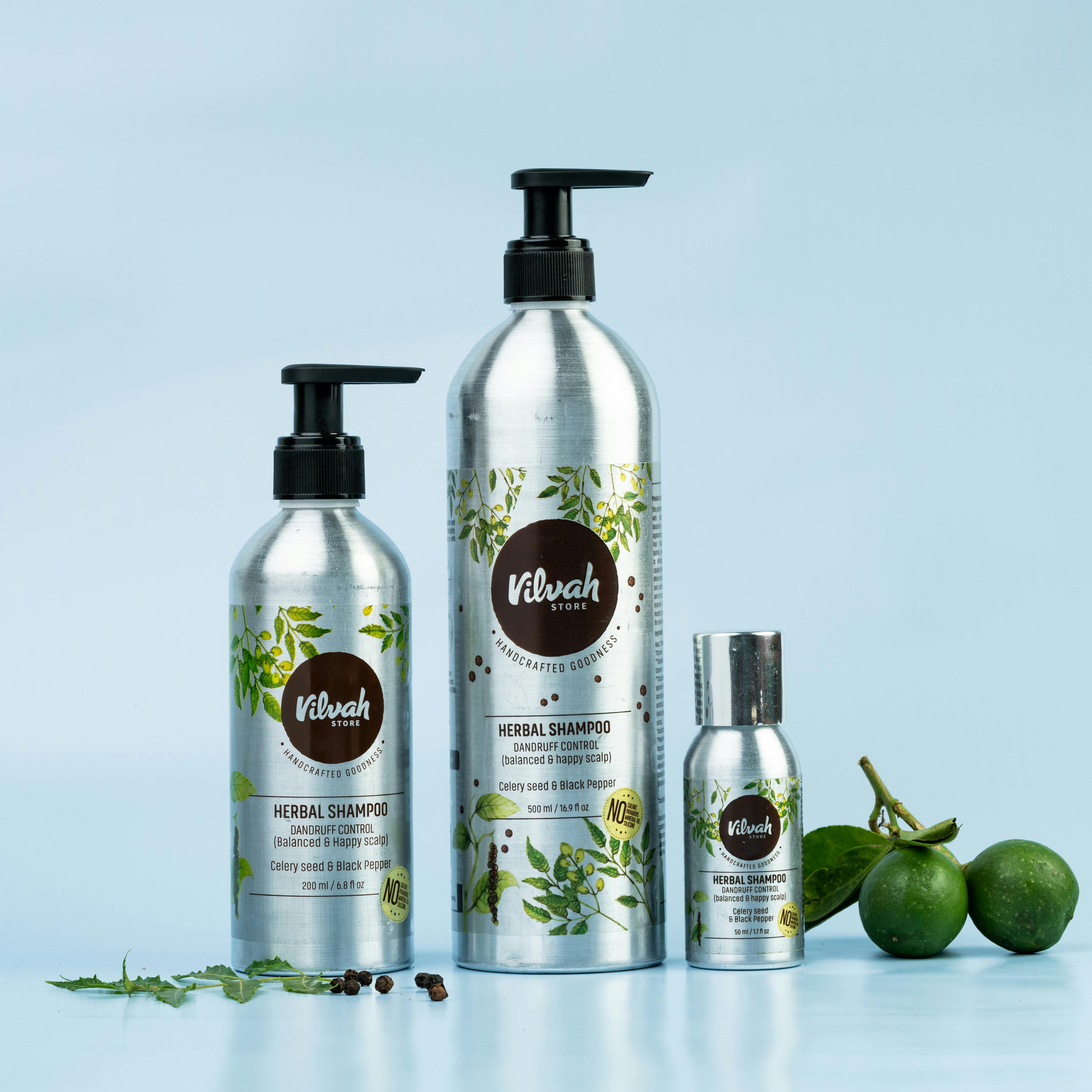 Display of herbal shampoo bottles with limes on a blue background, showcasing natural beauty products.