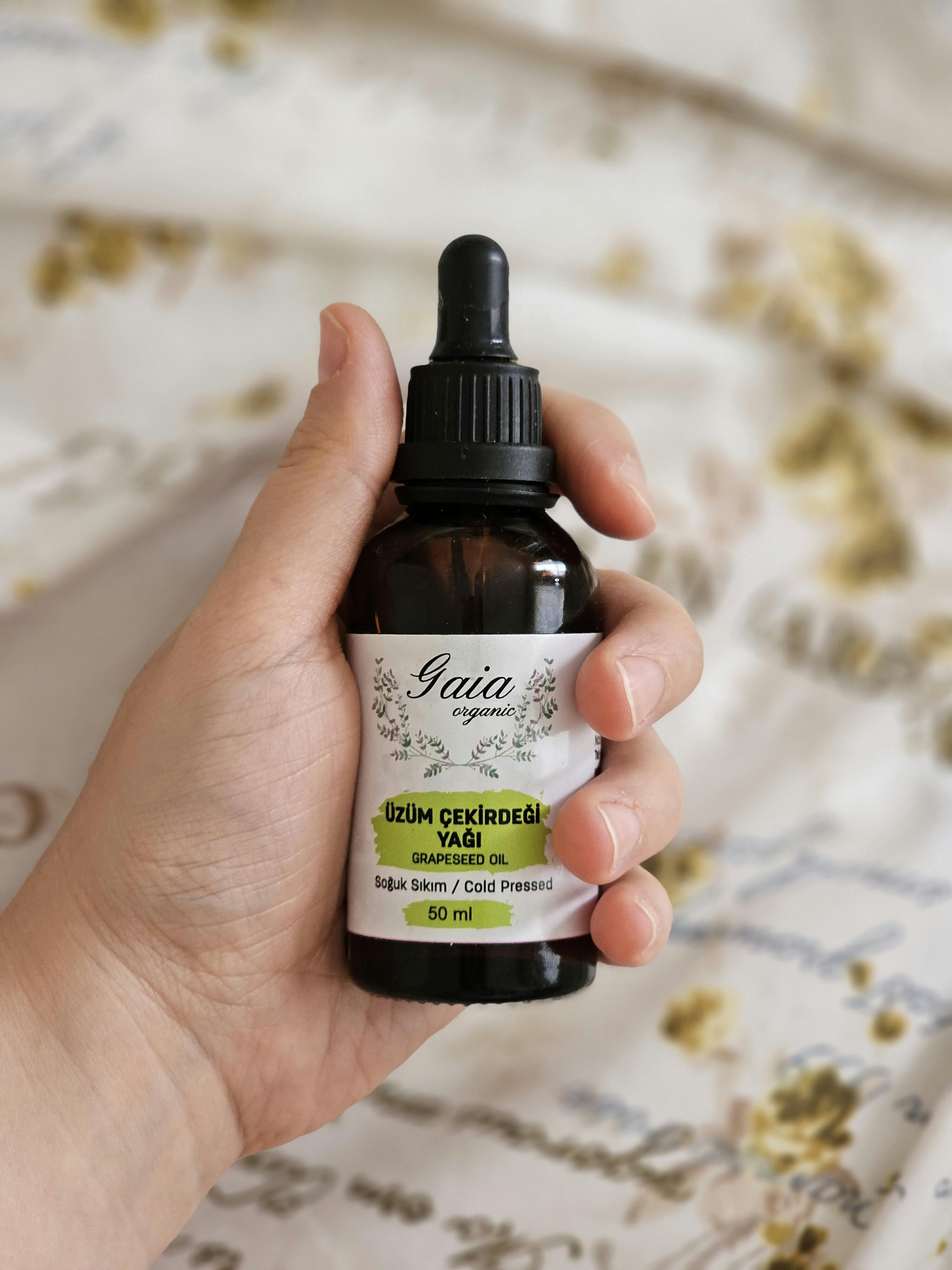 Close-up of a hand holding a bottle of Gaia organic grapeseed oil, perfect for skincare.