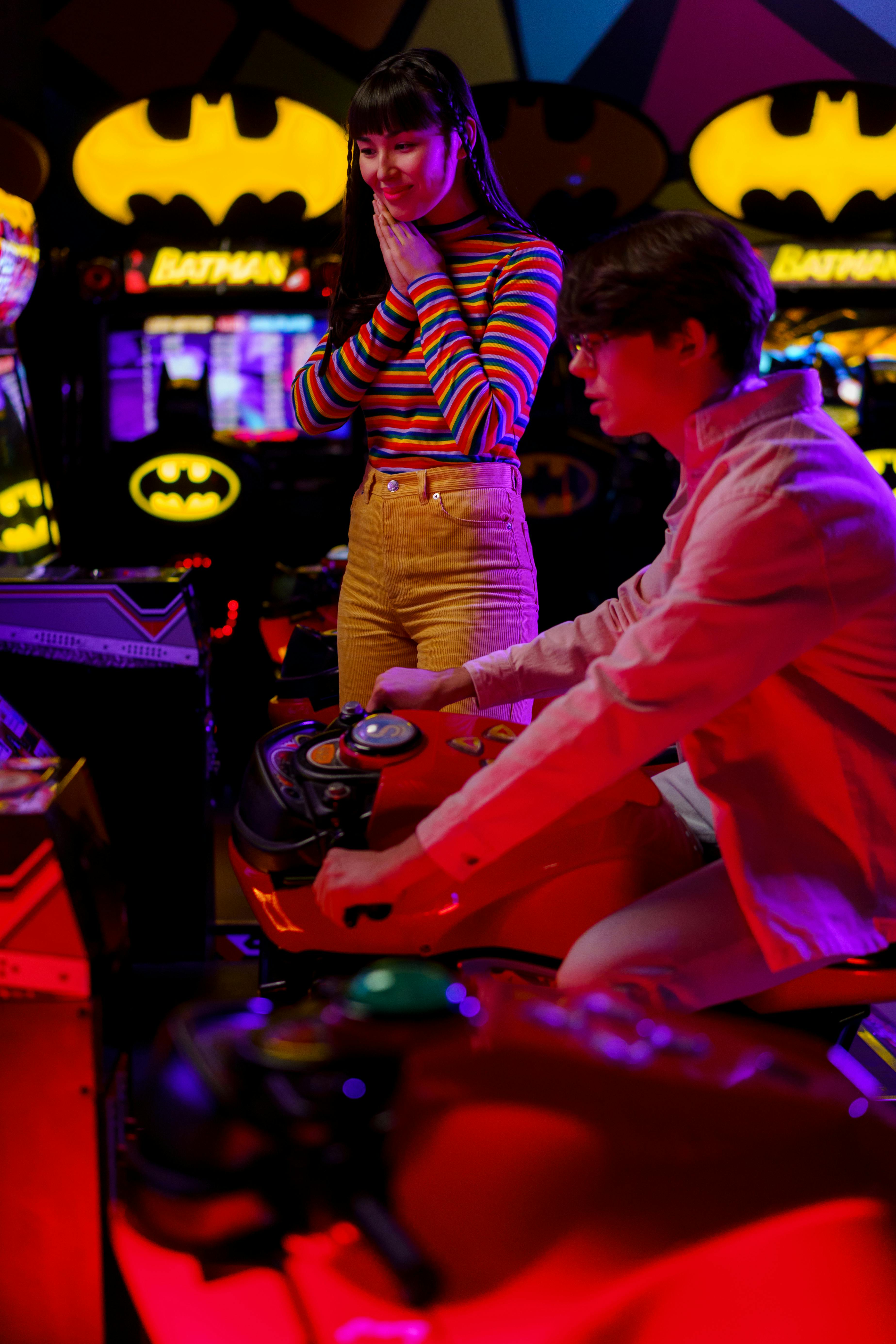A couple playing a motorcycle racing video game at an amusement arcade.