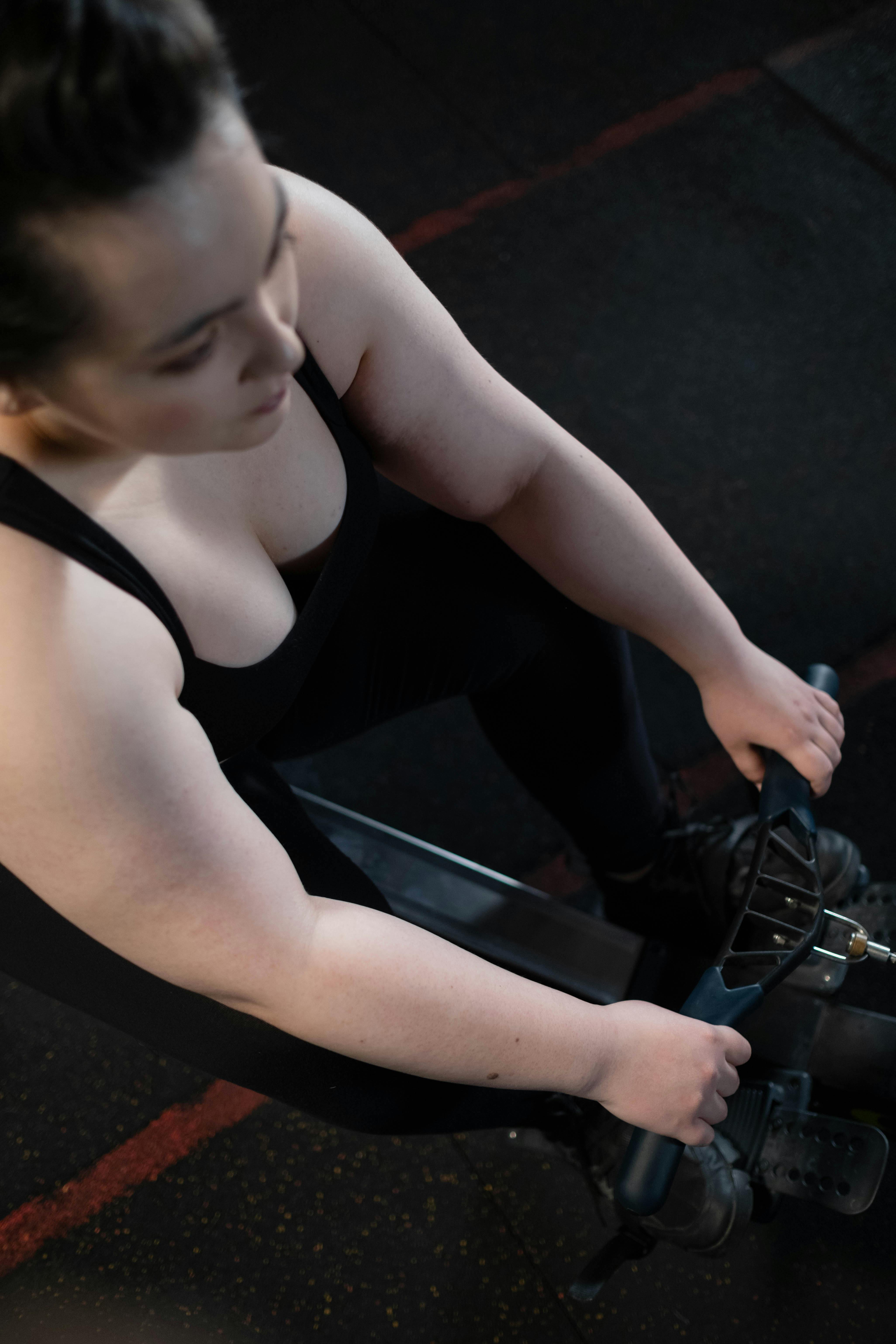 Top view of a woman working out on a rowing machine in the gym, focusing on fitness and wellness.
