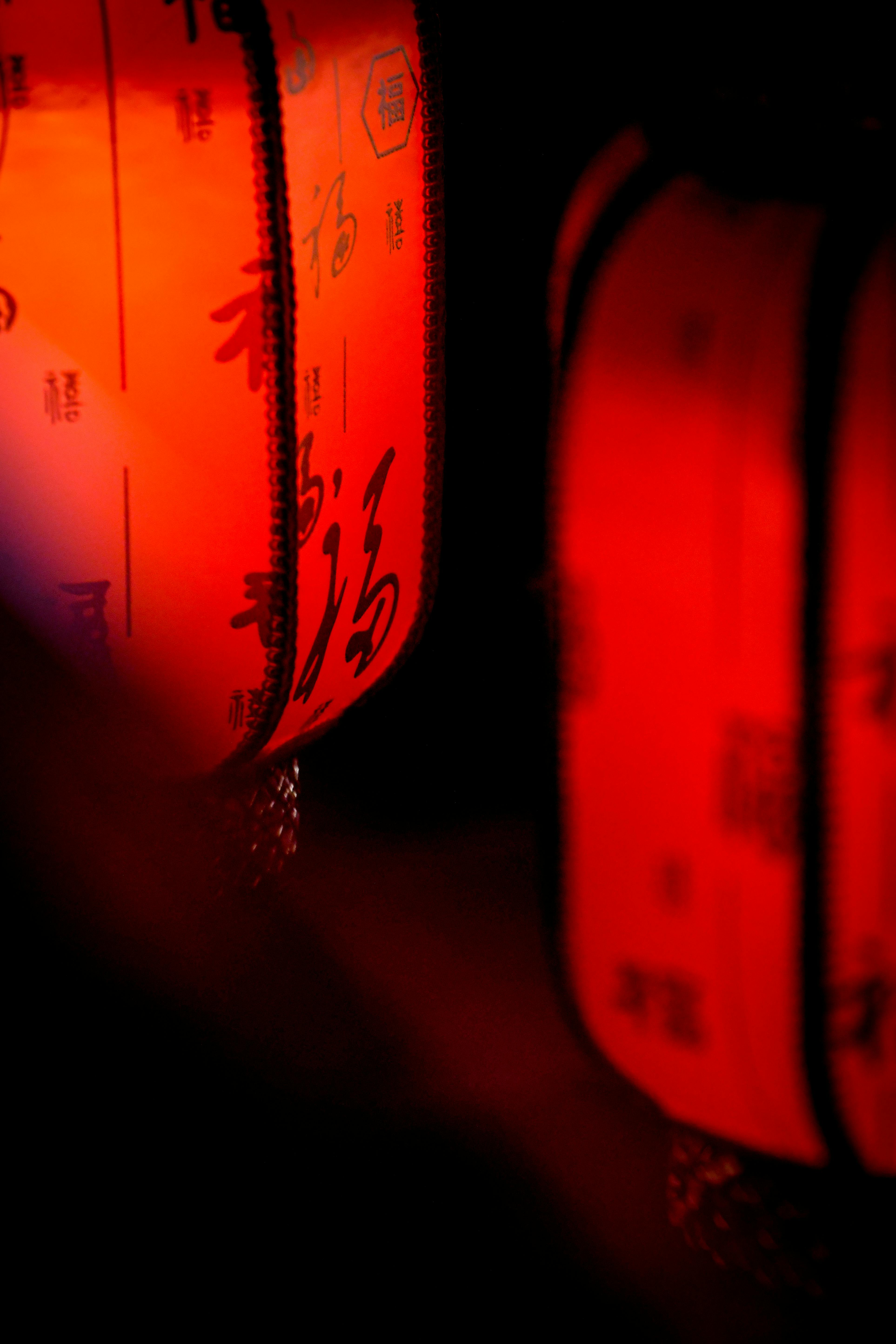 Close-up view of glowing red Chinese lanterns with calligraphy, evoking cultural tradition.
