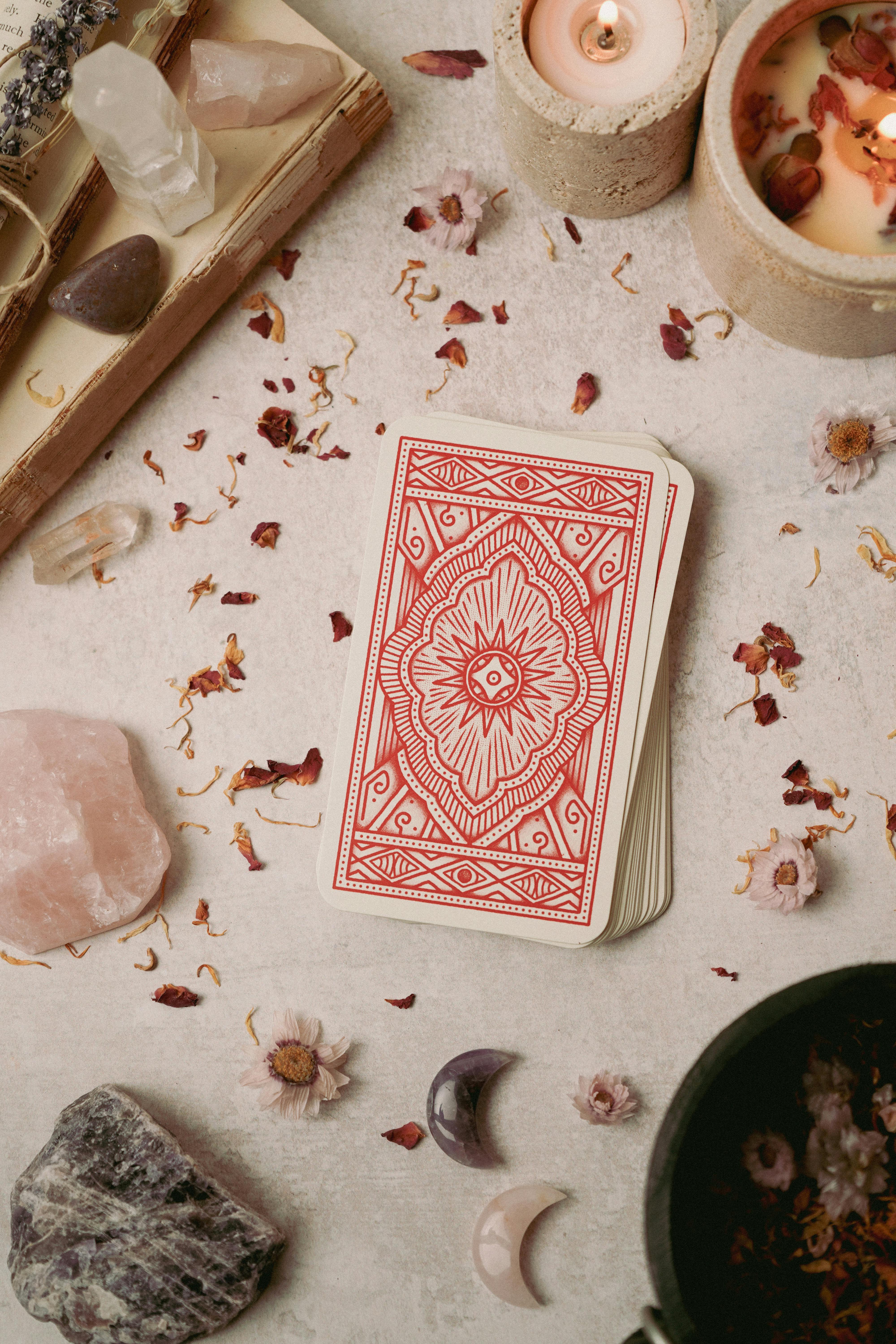 Flat lay of tarot cards surrounded by crystals and candles, evoking a mystical and calming atmosphere.
