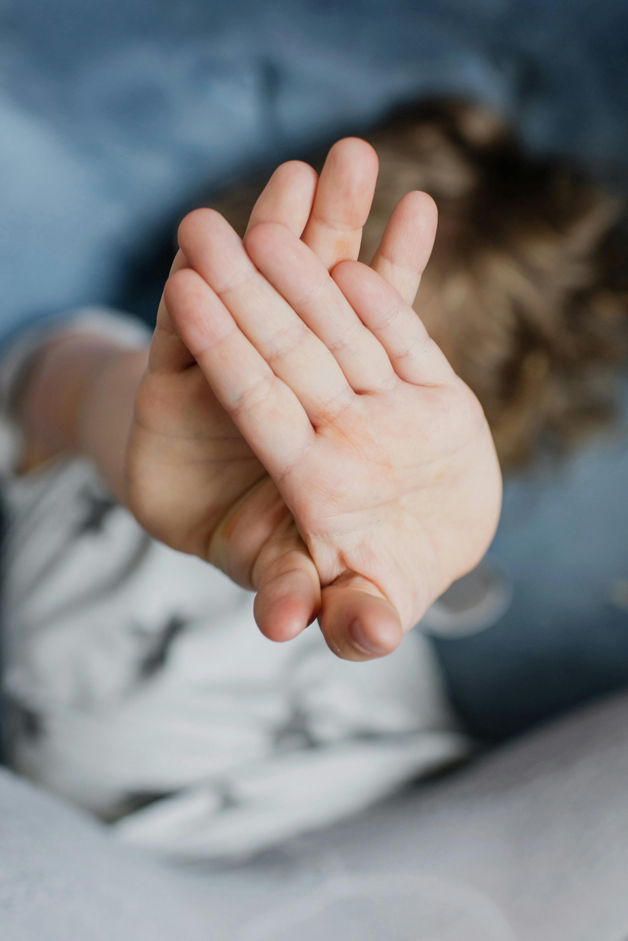 Close-up of a child's hands covering their face, creating a playful and mysterious vibe.