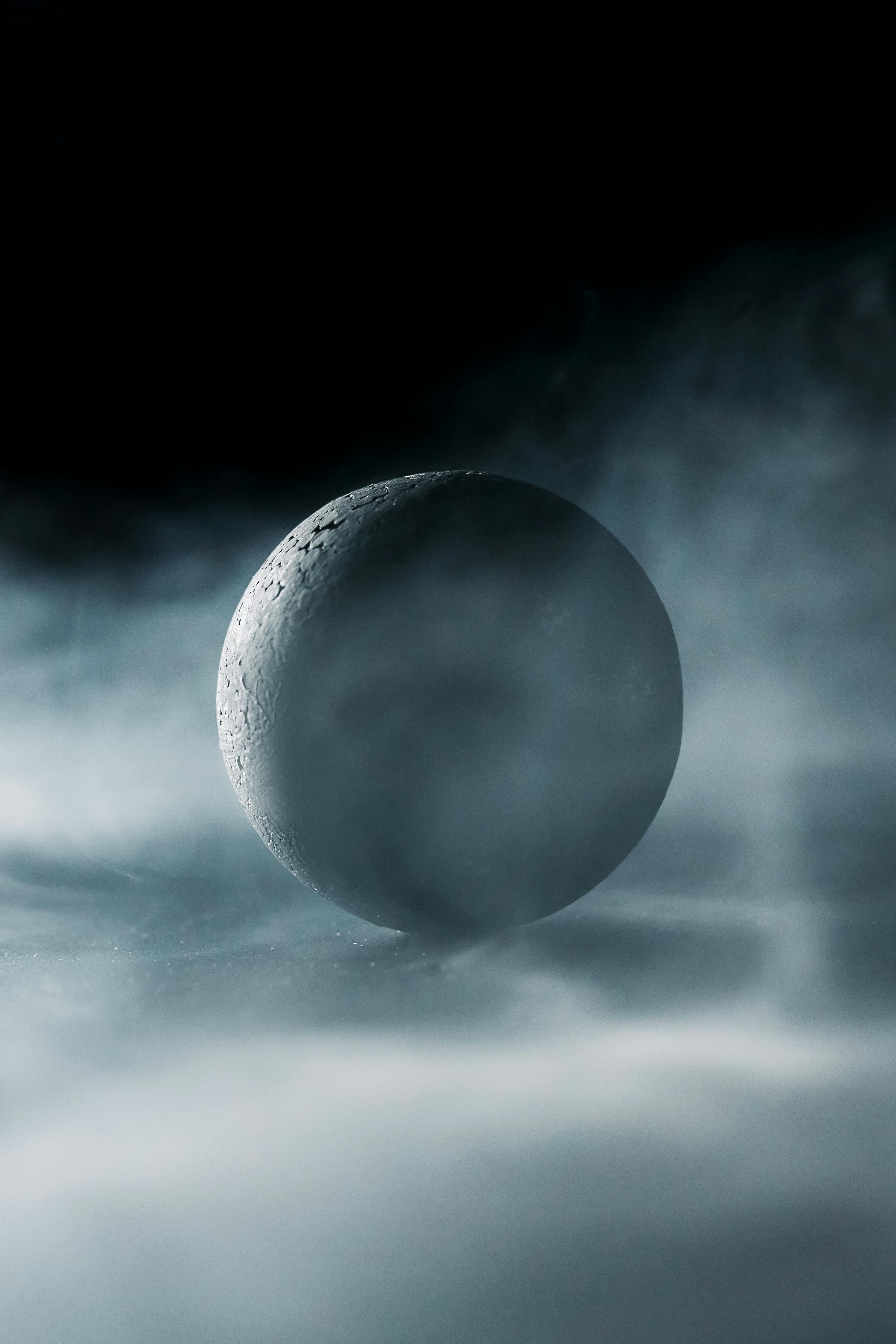 Moody image of a textured stone sphere surrounded by thick mist, evoking mystery and intrigue.