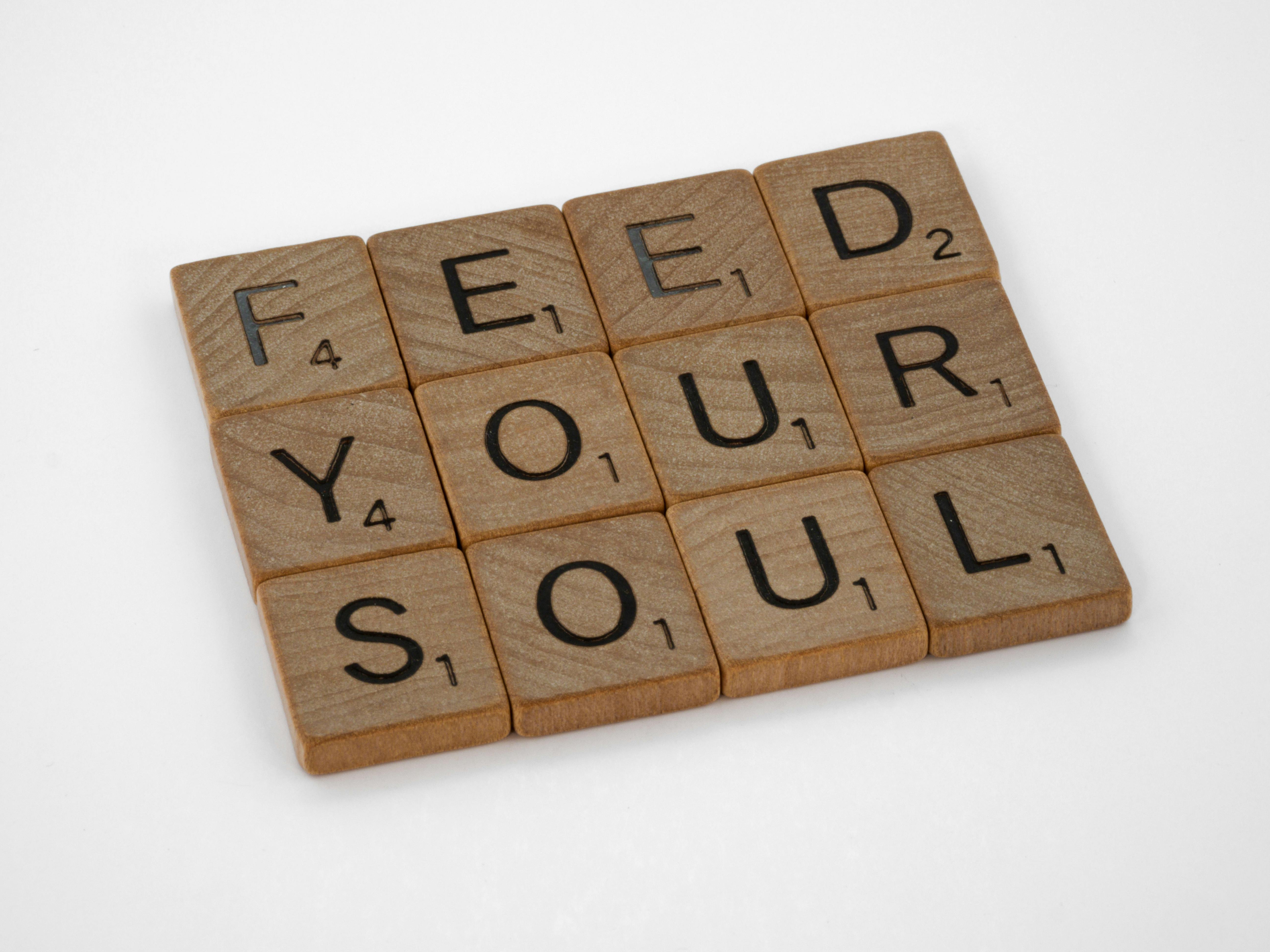 Close-up of Scrabble tiles spelling 'Feed Your Soul' on a white background.